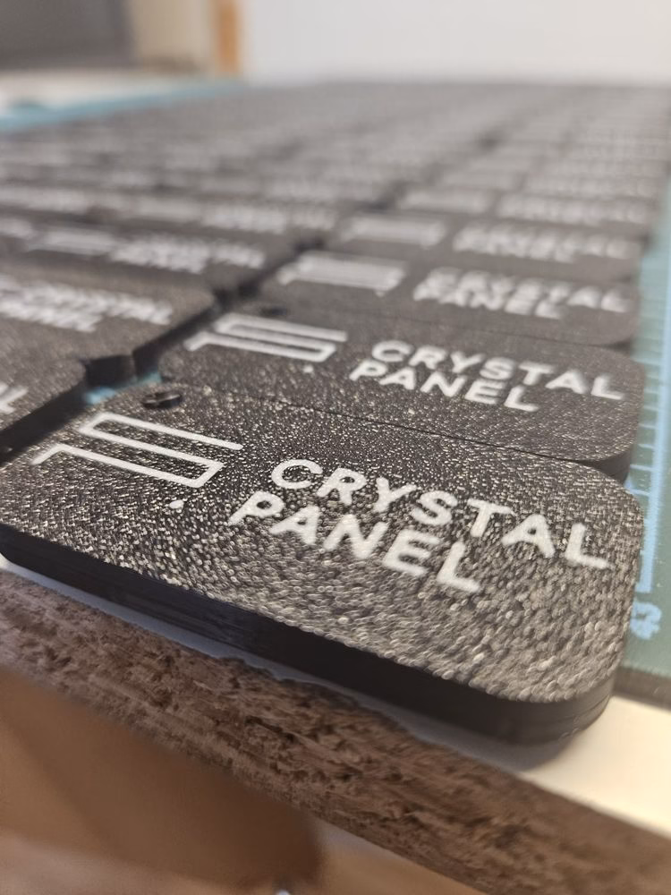 Zbliżenie na czarne breloki z białym logo Crystal Panel