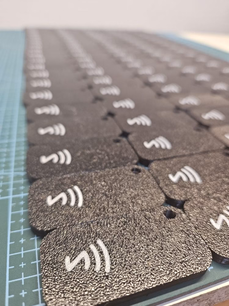 Seria czarnych breloków NFC z białym symbolem NFC, wydrukowanych w 3D
